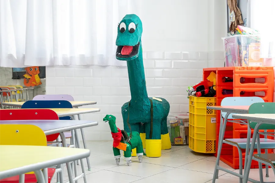 Sala de aula do Colégio Atlântico decorada com dinossauros e brinquedos educativos, ambiente alegre e acolhedor voltado ao desenvolvimento infantil.